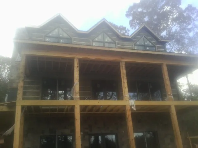 Dormers and porch framing on a large log home under construction — Roof Coating work by our crew in Tillman