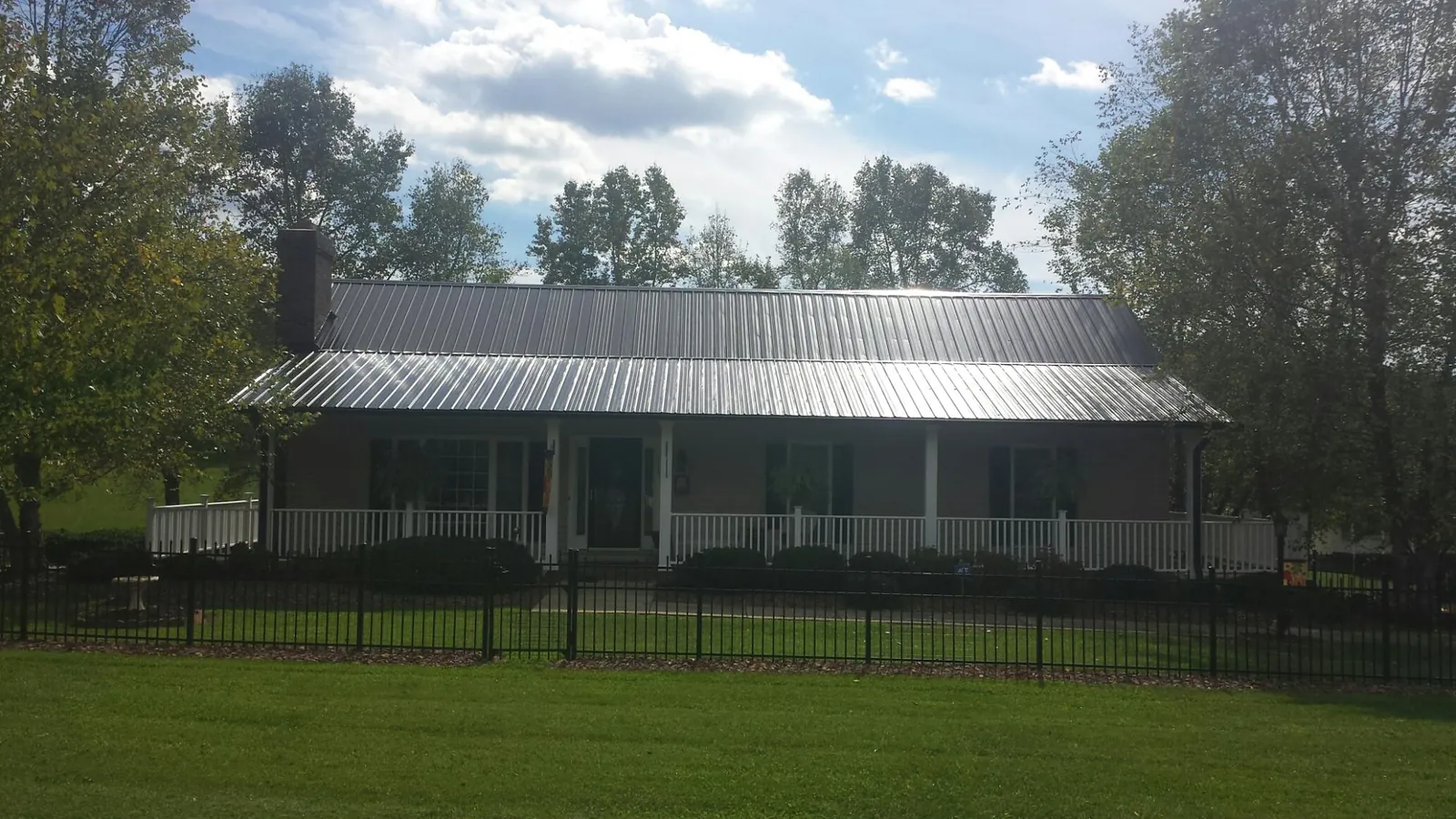 Gray metal roof on a brick ranch with a full width front porch — Gutter Guard Installation work by our crew in Tillman