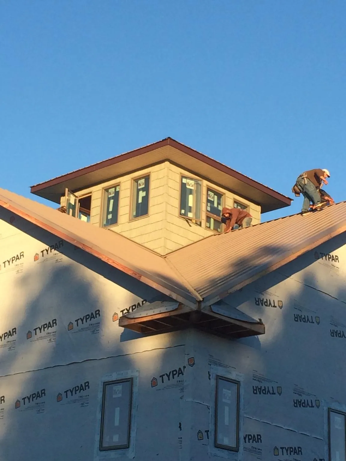 Roofers working around a rooftop cupola on a new metal roof at sunset — Roof Waterproofing in Tillman by Roofing Brothers